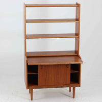 こちらのディスプレイシェルフは、チーク材とオーク材を組み合わせた柔らかなコントラストが魅力の北欧ビンテージ家具で、上部には奥行きの浅い棚板を2段備えた軽やかなディスプレイスペースに加えて天板部には引き棚が設けられており、雑貨や植物、本のレイアウトを楽しみながら作業スペースとしても活用でき、下部のスライド扉収納によって見せる収納と隠す収納を両立できるほか、細身の脚部が全体に浮遊感を与えて空間を圧迫しないバランスの良いデザインに仕上がっており、経年で深まった木肌の温もりも相まってリビングやダイニング、玄関周りにも取り入れやすい一台です。