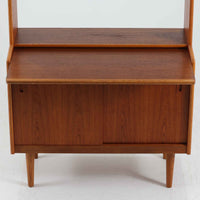 こちらのディスプレイシェルフは、チーク材とオーク材を組み合わせた柔らかなコントラストが魅力の北欧ビンテージ家具で、上部には奥行きの浅い棚板を2段備えた軽やかなディスプレイスペースに加えて天板部には引き棚が設けられており、雑貨や植物、本のレイアウトを楽しみながら作業スペースとしても活用でき、下部のスライド扉収納によって見せる収納と隠す収納を両立できるほか、細身の脚部が全体に浮遊感を与えて空間を圧迫しないバランスの良いデザインに仕上がっており、経年で深まった木肌の温もりも相まってリビングやダイニング、玄関周りにも取り入れやすい一台です。