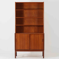 スウェーデン製のこちらのディスプレイシェルフは、チーク材の深みある木目が美しい上段のオープン棚と、下段のスライド扉収納を組み合わせた機能性の高い構成が特徴で、細身のフレームや角を丁寧に面取りした滑らかなフォルムが空間に柔らかな印象をもたらす北欧ビンテージ家具です。書籍や雑貨を見せながら収納でき、下段には日用品をすっきりと隠してしまえるため、リビングやダイニングの整理にも便利で、経年によって深まったチーク材の風合いがインテリアに温かみと落ち着きを添える一台です。