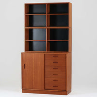 Nils Jonssonがデザインし、Hugo Troedsより発表されたモデルDomi 13のディスプレイシェルフです。チーク材の美しい木目と温かみのある色合いが空間に上質な北欧らしさをもたらします。上段・中段・下段のセクション構造で、それぞれを分けて使用できる柔軟な設計も魅力。下段は右側に引き出し、左側に高さ調整可能な棚を備え、実用性にも優れています。削り出しの取っ手や端正なフレームラインに職人技が感じられ、経年により深みを増した風合いがビンテージならではの存在感を放つ一品です。