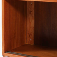 デンマークで製作されたチーク材のローボードです。幅100cmの小ぶりなサイズながら、温かみのある木目とシンプルな直線的フォルムが北欧らしい落ち着いた佇まいを演出します。前面には手掛け付きのスライド扉が備えられ、内部収納をすっきりと隠しながら使いやすさも確保。細身の脚部が軽やかな印象を与え、リビングや玄関、ベッドサイドなど様々な空間で活躍します。背板には壁掛け用の金具が取り付けられており、収納内部にはDIYによる木材の追加や小さな穴が見られますが、ビンテージ品ならではの味わいとして楽しめる一台です。