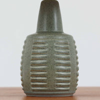 Einar Johansenがデザインし、Soholm Keramikが手掛けたテーブルランプです。高さ37cmの取り入れやすいサイズに、艶やかな陶磁器ベースとナチュラルなリネンシェードを組み合わせた、落ち着きある北欧ビンテージらしい一台。ベースには規則的な立体リブ装飾が施され、陰影豊かな表情と彫刻的な存在感を生み出しています。点灯時にはシェード越しの柔らかな光が釉薬の奥行きや貫入の表情を引き立て、チェストやサイドテーブル、ベッドサイドに穏やかな雰囲気を演出。Einar Johansenらしい造形美とSoholmの高い陶芸技術が感じられる、希少性の高いビンテージ照明です。
