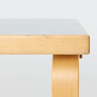 Alvar Aaltoがデザインし、Artek社より製造されたこちらのダイニングテーブルは、落ち着いたグレートーンのリノリウム天板と、美しい木肌を活かしたバーチ材の脚部を組み合わせた、北欧モダンを代表する名作です。L字型に曲げられた脚部は、アアルトらしい柔らかな造形美と高い機能性を兼ね備え、空間に軽やかな印象をもたらします。幅120cmの使い勝手のよいサイズで、ダイニングはもちろんワークスペースにも自然に馴染みます。なお、天板裏面には脚の付け替え跡が確認できたため、安心してお使いいただけるよう現状でしっかり固定しており、脚部の取り外しはできない仕様となっております。