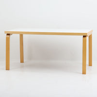 Artek(アルテック)社の「Table 81A」、Alvar Aalto(アルヴァ・アアルト)によるデザインのビンテージダイニングテーブルです。バーチ材を曲げて成形した象徴的なLレッグに、ホワイトのリノリウム天板を組み合わせた端正な佇まいが特徴。装飾を抑えたシンプルな構成ながら、柔らかな脚部の曲線にアアルトらしい造形美が表れています。幅150cmで食卓からワークテーブルまで使いやすく、時代を超えて空間に馴染む普遍的な魅力を備えています。