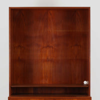 Hans J. Wegnerがデザインし、Ry Moblerが製作したディスプレイシェルフです。美しい木目をもつチーク材を主体に、内部や構造部にはオーク材、金具には真鍮を組み合わせた上質なつくりが魅力。上部のオープン棚は飾り棚として器やオブジェ、本を美しく見せ、下部の開き戸収納は細かい日用品や書類をすっきり隠して収納できます。直線的で端正なフォルムの中に、ウェグナーらしい丁寧な木工技術と素材の美しさが息づき、経年で深みを増した色艶が空間に格別の存在感を添える一品です。リビングや書斎、ショップ什器としてもおすすめです。