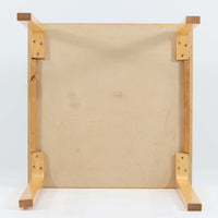 Alvar Aaltoがデザインし、Artekより製作された「81C」ダイニングテーブルです。バーチ材を用いたフレームに、天板には落ち着いた質感のリノリウムを組み合わせたシンプルで機能的なデザインが特徴。脚部にはアアルトを象徴するL字型の曲木構造が採用されており、軽やかで柔らかな印象を与えます。幅75cmの正方形サイズはダイニングはもちろんワークテーブルとしても使いやすく、日常の空間に北欧デザインの美しさと実用性をもたらすビンテージ家具です。本個体は、脚部の5枚レイヤー構造、1973年以降に採用されたプラスネジ、および天板裏の3段構成スタンプの仕様から、1973年~1990年代始めに掛けて製造されたと思われます。