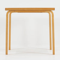 Alvar Aaltoがデザインし、Artekより製作された「81C」ダイニングテーブルです。バーチ材を用いたフレームに、天板には落ち着いた質感のリノリウムを組み合わせたシンプルで機能的なデザインが特徴。脚部にはアアルトを象徴するL字型の曲木構造が採用されており、軽やかで柔らかな印象を与えます。幅75cmの正方形サイズはダイニングはもちろんワークテーブルとしても使いやすく、日常の空間に北欧デザインの美しさと実用性をもたらすビンテージ家具です。本個体は、脚部の5枚レイヤー構造、1973年以降に採用されたプラスネジ、および天板裏の3段構成スタンプの仕様から、1973年~1990年代始めに掛けて製造されたと思われます。