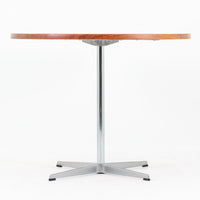 Arne Jacobsenがデザインし、Fritz Hansenが製作した円形ダイニングテーブルです。直径90cmのチーク無垢天板は、豊かな木目と滑らかな円形フォルムが美しく、空間に柔らかな印象をもたらします。シャープなスチール製の一本脚と4本スポークベースが軽快で洗練された佇まいを生み、ヤコブセンらしい機能美が際立つ一台。2~4人で使いやすいサイズ感で、ダイニングテーブルとしてはもちろん、カフェテーブルやラウンジ空間での打ち合わせ用テーブルとしてもおすすめです。中でもチーク無垢材仕様の個体は流通数が少なく珍しく、北欧ビンテージ市場でも希少性の高いモデルとして魅力を放ちます。経年により深みを増した木肌と無駄のない構造が、空間に上質な存在感を添えてくれます。
