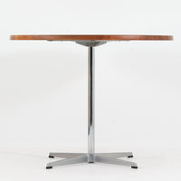 Arne Jacobsenがデザインし、Fritz Hansenが製作した円形ダイニングテーブルです。直径90cmのチーク無垢天板は、豊かな木目と滑らかな円形フォルムが美しく、空間に柔らかな印象をもたらします。シャープなスチール製の一本脚と4本スポークベースが軽快で洗練された佇まいを生み、ヤコブセンらしい機能美が際立つ一台。2~4人で使いやすいサイズ感で、ダイニングテーブルとしてはもちろん、カフェテーブルやラウンジ空間での打ち合わせ用テーブルとしてもおすすめです。中でもチーク無垢材仕様の個体は流通数が少なく珍しく、北欧ビンテージ市場でも希少性の高いモデルとして魅力を放ちます。経年により深みを増した木肌と無駄のない構造が、空間に上質な存在感を添えてくれます。