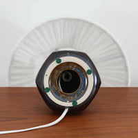 デンマークの陶磁器メーカーSoholm Keramik(スーホルム)による、Einar Johansen(アイナー・ヨハンセン)デザインのビンテージテーブルランプ。すらりと伸びた首元と、裾に向かって緩やかに広がるベースが美しい、端正で洗練されたシルエットが特徴です。深みのあるブルーグレーの釉薬は、光の当たり方によって繊細な色の変化を見せ、艶やかな質感が陶磁器ならではの魅力を引き立てています。ベース下部には縦方向のレリーフ模様が規則的に施され、立体的な陰影と心地よいリズムを生み出しています。プリーツを施したリネンシェードからは柔らかな光が広がり、落ち着いた雰囲気を演出します。リビングのサイドボードや寝室など、空間に上品なアクセントを添える照明としておすすめです。