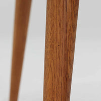 Hans J. Wegnerがデザインし、Andreas Tuckが製造を手掛けたAT8。チーク材の円形天板とオーク材の脚部を組み合わせ、異なる木材の表情を巧みに生かした一台です。直径98cmの伸びやかな天板を、外側へ緩やかに開く4本のテーパードレッグが軽快に支えるシンプルな構成で、素材とプロポーションの美しさが際立ちます。ソファを囲むリビングの主役として取り入れやすく、ウェグナーらしい端正な造形と年月を重ねた木部の風合いを味わえるビンテージ品です。