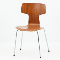 アルネ・ヤコブセンがデザインし、Fritz Hansenが製造した「T Chair」です。チーク材の成形合板による背座一体型のシェルは、背面上部を左右に広げた特徴的なシルエットと、身体に沿う緩やかな曲面が魅力。細身の金属脚との組み合わせが軽快で、ダイニングはもちろん、書斎や玄関のアクセントチェアにもおすすめです。美しい木目と時を重ねた風合い、合理的な構造に宿る北欧ビンテージらしい存在感を楽しめます。