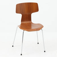 アルネ・ヤコブセンがデザインし、Fritz Hansenが製造した「T Chair」です。チーク材の成形合板による背座一体型のシェルは、背面上部を左右に広げた特徴的なシルエットと、身体に沿う緩やかな曲面が魅力。細身の金属脚との組み合わせが軽快で、ダイニングはもちろん、書斎や玄関のアクセントチェアにもおすすめです。美しい木目と時を重ねた風合い、合理的な構造に宿る北欧ビンテージらしい存在感を楽しめます。