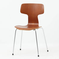 アルネ・ヤコブセンがデザインし、Fritz Hansenが製造した「T Chair」です。チーク材の成形合板による背座一体型のシェルは、背面上部を左右に広げた特徴的なシルエットと、身体に沿う緩やかな曲面が魅力。細身の金属脚との組み合わせが軽快で、ダイニングはもちろん、書斎や玄関のアクセントチェアにもおすすめです。美しい木目と時を重ねた風合い、合理的な構造に宿る北欧ビンテージらしい存在感を楽しめます。