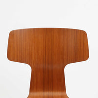 アルネ・ヤコブセンがデザインし、Fritz Hansenが製造した「T Chair」です。チーク材の成形合板による背座一体型のシェルは、背面上部を左右に広げた特徴的なシルエットと、身体に沿う緩やかな曲面が魅力。細身の金属脚との組み合わせが軽快で、ダイニングはもちろん、書斎や玄関のアクセントチェアにもおすすめです。美しい木目と時を重ねた風合い、合理的な構造に宿る北欧ビンテージらしい存在感を楽しめます。