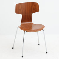 アルネ・ヤコブセンがデザインし、Fritz Hansenが製造した「T Chair」です。チーク材の成形合板による背座一体型のシェルは、背面上部を左右に広げた特徴的なシルエットと、身体に沿う緩やかな曲面が魅力。細身の金属脚との組み合わせが軽快で、ダイニングはもちろん、書斎や玄関のアクセントチェアにもおすすめです。美しい木目と時を重ねた風合い、合理的な構造に宿る北欧ビンテージらしい存在感を楽しめます。