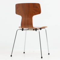 アルネ・ヤコブセンがデザインし、Fritz Hansenが製造した「T Chair」です。チーク材の成形合板による背座一体型のシェルは、背面上部を左右に広げた特徴的なシルエットと、身体に沿う緩やかな曲面が魅力。細身の金属脚との組み合わせが軽快で、ダイニングはもちろん、書斎や玄関のアクセントチェアにもおすすめです。美しい木目と時を重ねた風合い、合理的な構造に宿る北欧ビンテージらしい存在感を楽しめます。