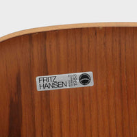 アルネ・ヤコブセンがデザインし、Fritz Hansenが製造した「T Chair」です。チーク材の成形合板による背座一体型のシェルは、背面上部を左右に広げた特徴的なシルエットと、身体に沿う緩やかな曲面が魅力。細身の金属脚との組み合わせが軽快で、ダイニングはもちろん、書斎や玄関のアクセントチェアにもおすすめです。美しい木目と時を重ねた風合い、合理的な構造に宿る北欧ビンテージらしい存在感を楽しめます。