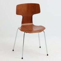 アルネ・ヤコブセンがデザインし、Fritz Hansenが製造した「T Chair」です。チーク材の成形合板による背座一体型のシェルは、背面上部を左右に広げた特徴的なシルエットと、身体に沿う緩やかな曲面が魅力。細身の金属脚との組み合わせが軽快で、ダイニングはもちろん、書斎や玄関のアクセントチェアにもおすすめです。美しい木目と時を重ねた風合い、合理的な構造に宿る北欧ビンテージらしい存在感を楽しめます。