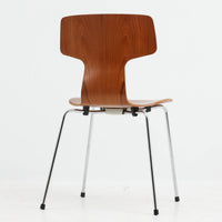 アルネ・ヤコブセンがデザインし、Fritz Hansenが製造した「T Chair」です。チーク材の成形合板による背座一体型のシェルは、背面上部を左右に広げた特徴的なシルエットと、身体に沿う緩やかな曲面が魅力。細身の金属脚との組み合わせが軽快で、ダイニングはもちろん、書斎や玄関のアクセントチェアにもおすすめです。美しい木目と時を重ねた風合い、合理的な構造に宿る北欧ビンテージらしい存在感を楽しめます。