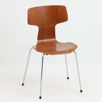 アルネ・ヤコブセンがデザインし、Fritz Hansenが製造した「T Chair」です。チーク材の成形合板による背座一体型のシェルは、背面上部を左右に広げた特徴的なシルエットと、身体に沿う緩やかな曲面が魅力。細身の金属脚との組み合わせが軽快で、ダイニングはもちろん、書斎や玄関のアクセントチェアにもおすすめです。美しい木目と時を重ねた風合い、合理的な構造に宿る北欧ビンテージらしい存在感を楽しめます。