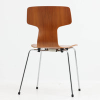 アルネ・ヤコブセンがデザインし、Fritz Hansenが製造した「T Chair」です。チーク材の成形合板による背座一体型のシェルは、背面上部を左右に広げた特徴的なシルエットと、身体に沿う緩やかな曲面が魅力。細身の金属脚との組み合わせが軽快で、ダイニングはもちろん、書斎や玄関のアクセントチェアにもおすすめです。美しい木目と時を重ねた風合い、合理的な構造に宿る北欧ビンテージらしい存在感を楽しめます。
