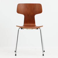 アルネ・ヤコブセンがデザインし、Fritz Hansenが製造した「T Chair」です。チーク材の成形合板による背座一体型のシェルは、背面上部を左右に広げた特徴的なシルエットと、身体に沿う緩やかな曲面が魅力。細身の金属脚との組み合わせが軽快で、ダイニングはもちろん、書斎や玄関のアクセントチェアにもおすすめです。美しい木目と時を重ねた風合い、合理的な構造に宿る北欧ビンテージらしい存在感を楽しめます。