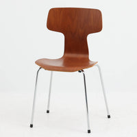 アルネ・ヤコブセンがデザインし、Fritz Hansenが製造した「T Chair」です。チーク材の成形合板による背座一体型のシェルは、背面上部を左右に広げた特徴的なシルエットと、身体に沿う緩やかな曲面が魅力。細身の金属脚との組み合わせが軽快で、ダイニングはもちろん、書斎や玄関のアクセントチェアにもおすすめです。美しい木目と時を重ねた風合い、合理的な構造に宿る北欧ビンテージらしい存在感を楽しめます。