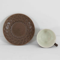 デンマークを代表するデザイナー、イェンス・H・クイストゴーによる「Azur(アズール)」シリーズのヴィンテージカッププ&ソーサーです。1960年代にKronjydenから制作が始まったシリーズは、その後Nissen、Bing&Grondahlと引き継がれ長く愛されたシリーズとなりました。落ち着いたブラウンとプラム色の繊細なフラワーレリーフが施されたストーンウェアは、自然の美しさを食卓にそっと運びます。特にAzurシリーズはヴィンテージ市場でも流通量が極めて少なく高価な逸品となります。