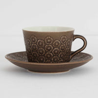 デンマークを代表するデザイナー、イェンス・H・クイストゴーによる「Azur(アズール)」シリーズのヴィンテージカッププ&ソーサーです。1960年代にKronjydenから制作が始まったシリーズは、その後Nissen、Bing&Grondahlと引き継がれ長く愛されたシリーズとなりました。落ち着いたブラウンとプラム色の繊細なフラワーレリーフが施されたストーンウェアは、自然の美しさを食卓にそっと運びます。特にAzurシリーズはヴィンテージ市場でも流通量が極めて少なく高価な逸品となります。