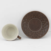 デンマークを代表するデザイナー、イェンス・H・クイストゴーによる「Azur(アズール)」シリーズのヴィンテージカッププ&ソーサーです。1960年代にKronjydenから制作が始まったシリーズは、その後Nissen、Bing&Grondahlと引き継がれ長く愛されたシリーズとなりました。落ち着いたブラウンとプラム色の繊細なフラワーレリーフが施されたストーンウェアは、自然の美しさを食卓にそっと運びます。特にAzurシリーズはヴィンテージ市場でも流通量が極めて少なく高価な逸品となります。