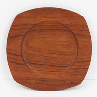 1960年代、デンマーク・モダンの黄金期にポール・クヌーセンが手がけたチーク無垢材のプレートです。「実用工芸」を意味するブランド名の通り、木の質感を活かした滑らかな曲線と、洗練されたミニマルな造形美が魅力。半世紀を経て深く色づいたチーク材は「木の宝石」と称されるほど美しく、食卓に温かな品格を添えます。食器としてはもちろん、インテリアトレイとしても重宝する、一期一会のヴィンテージ名作です。