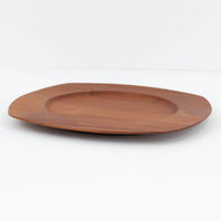 1960年代、デンマーク・モダンの黄金期にポール・クヌーセンが手がけたチーク無垢材のプレートです。「実用工芸」を意味するブランド名の通り、木の質感を活かした滑らかな曲線と、洗練されたミニマルな造形美が魅力。半世紀を経て深く色づいたチーク材は「木の宝石」と称されるほど美しく、食卓に温かな品格を添えます。食器としてはもちろん、インテリアトレイとしても重宝する、一期一会のヴィンテージ名作です。