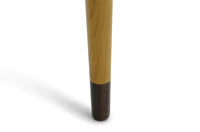 スレンダーな脚が特徴のセンターテーブルです。天板は長方形でシンプルに、コーナーにジョイントされた四角い脚は先端に向かって徐々に丸くなるよう削りだしており、スタイリッシュで美しいデザインに仕上げています。ハンドメイドで一つ一つ丁寧に削り出した脚は天板との一体感があり、まるで完成品かのような仕上がりです。また、汚れやすいとされる足先には汚れが目立ちにくいように、そしてまるで美しい脚に見えるようにと、ひと手間かけてローズウッド材(現在はチーク材のローズウッドカラー塗装への仕様変更となっています)をジョイントしています。