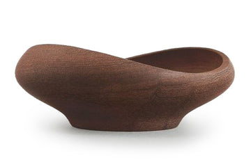 彫刻的なFJボウルは、1951年にデザインされたチンウッド・ボウル・シリーズの中でも最も小さいものです。フィンランドの有名な木製と形と色のバランスの取れた有機的な調和が特長です。材料を最も自然に見せるために、Juhlはティークウッドの有機的なテクスチャと楕円形のうねりのあるリムを対照して脆弱な平衡を打ちます。天然木のシンプルさは幾何学的な複雑さと並置されており、インテリアの設計時に目を引く美しいハーモニーを生み出しています。FJボウルはチーク材の片から作られた手であり、透明なチークオイルで処理されています。