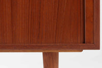 こちらは、カイ・クリスチャンセンによる小ぶりなローボードです。シンプルなデザインが特徴的で、ミニマリストなインテリアに調和します。本体には上質なチーク材が使用されており、美しい木目が目を引きます。北欧家具らしい蛇腹式扉が採用されており、開けた際にスペースを取らず、スマートな印象を与えます。内部にはレコード収納スペースが設けられており、レコードだけでなく書籍、DVDやBlu-rayディスク、ゲームソフト、デジタルメディアプレーヤーやゲームコンソールなど、さまざまなアイテムを収納できます。さらに、ハードウェアやアクセサリー、収納ボックスなどの整理に最適です。