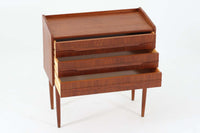 北欧ビンテージの3段チェストです。中央に取っ手が配置され、すっきりとした脚が特徴的です。チーク材が使用されており、天板は物が落ちにくいような設計になっています。シンプルで洗練されたデザインでありながら、機能性も考慮された、魅力的な家具です。