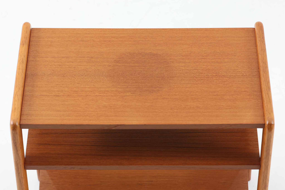 北欧で使用されていた、ドイツ製のサイドテーブルをご紹介いたします。このテーブルは、北欧家具を意識したデザインでありながら、独自の時代の流れを感じさせる魅力を持っています。上質なチーク材が使用されており綺麗な木目です。本体には傾斜のついた棚板も付いており、マガジンラックとして魅せる収納が出来そうです。