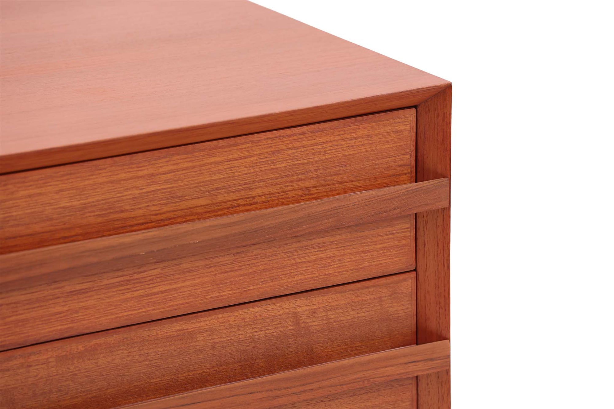 チーク材の４段チェストです。刃物のようなデザインの取っ手がチェスト本体と一体化することで収納時、非常にモダンで美しい印象を与えます。またこちらの長い取っ手は開け閉め時、ストレス無く、使い勝手がよいのも特徴です。チェスト本体の外枠が正面に対してフラットではなく斜めになっているなど高級感のあるデザインに仕上げています。