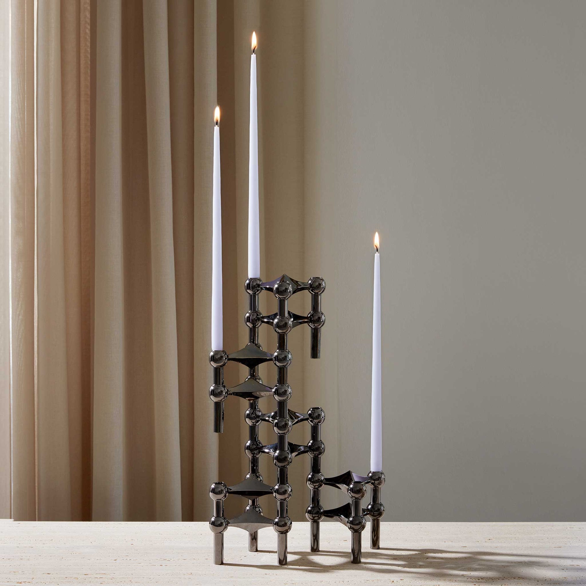 Stoff（ストッフ）は、デンマーク発のデザインブランドで、1960年代の名作「Stoff Nagel（ストッフ・ナゲル）」キャンドルホルダーの復刻から始まりました。建築家Werner Stoff（ヴェルナー・ストッフ）と、ドイツのHans Nagel（ハンス・ナゲル）によって生み出されたこのモジュール式キャンドルホルダーは、彫刻のような幾何学美と、自由な組み合わせによる創造性を兼ね備えたインテリアアートです。現在のStoffは、オリジナルの精神を受け継ぎながら、現代のライフスタイルに合う素材や仕上げを追加し、キャンドルホルダーだけでなくフラワーベースやボウル、ウォールハンガーなど洗練されたアイテムを展開。ミッドセンチュリーや北欧インテリアに調和し、空間に立体感と静謐な存在感を与えます。構築と装飾の境界を超えたStoffの作品は、機能性と造形美が共存する稀有なプロダクトです。