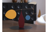 Volta Mobiles（ヴォルタ・モビール）は、2015年にフランス・パリで誕生したアートモビール専門ブランドです。ミッドセンチュリーの芸術や建築からインスピレーションを受けたデザインは、シンプルでありながら空間に躍動感と詩的な美しさをもたらします。ブランド創設後、アトリエはスペイン・バルセロナへと移り、すべての製品が職人の手作業で製造されています。熟練した職人の手によりひとつひとつ丁寧に組み立てられ、軽量なアルミニウムやスチールなどの高品質素材を使用。カラーリングも美しく、リビングや寝室、子供部屋、オフィスなど、幅広いインテリアに調和します。アートとしての価値と機能美を兼ね備えたVoltaのモビールは、北欧インテリアやナチュラルモダンを好む方におすすめのデザイン雑貨です。おしゃれな空間演出やギフトにも最適な逸品で、おしゃれなインテリア雑貨として、また贈り物や新築祝いにも人気の高いプロダクトです。