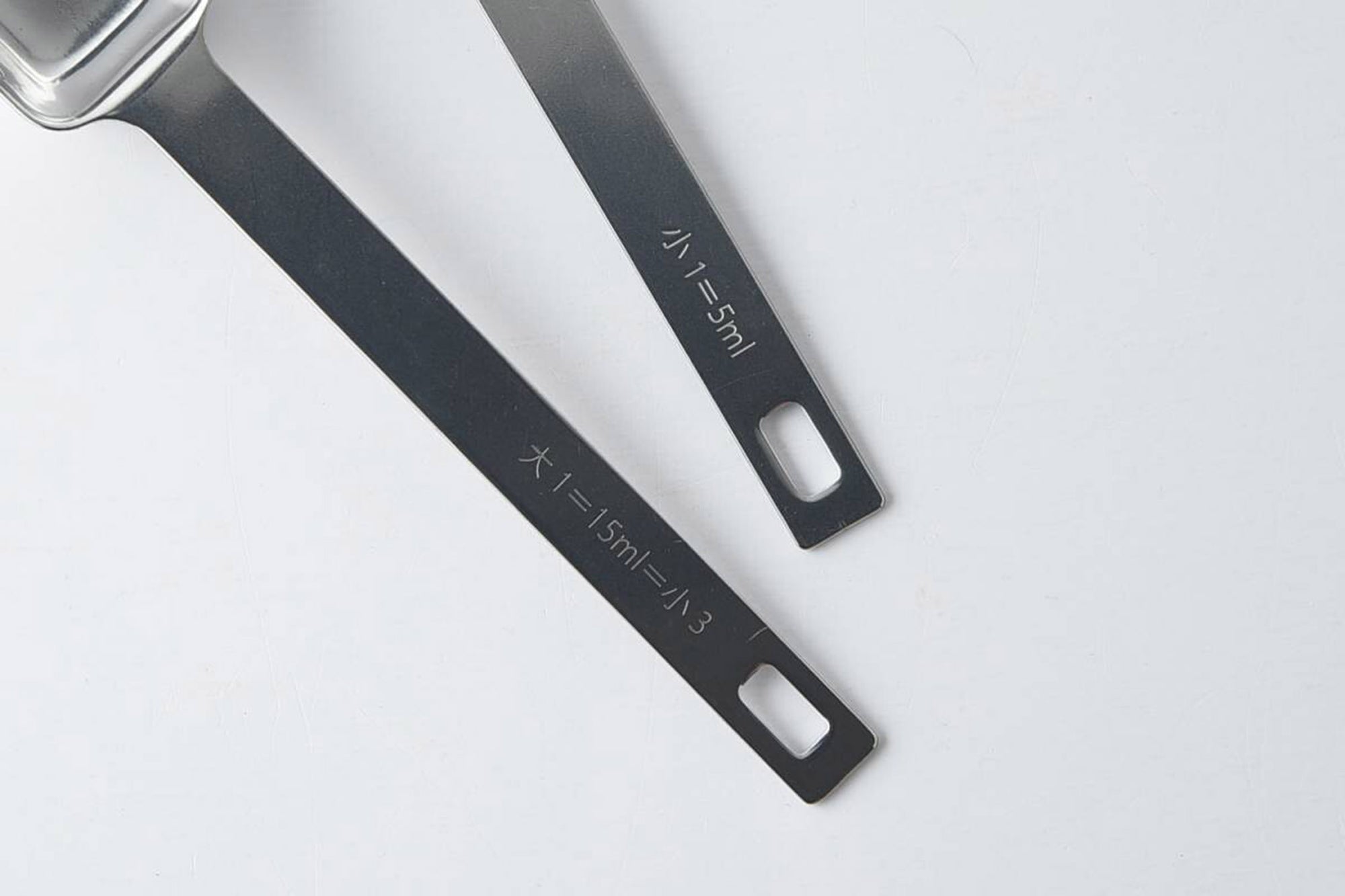 既存の計量スプーンの悩み事は、口の小さな容器には入らないことが多い事。そして、プラスティックややわらかいステンレスだと味噌や練りごまなどの固い調味料を取るときに曲がってしまうことがある事でした。いつもの計量スプーンにも少しずつ使いづらいところがある部分を、プロの目で見て徹底的に使いやすさを追求したのがこの「四角い計量スプーン」です。