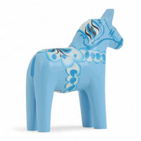 Grannas A. Olsson Hemslojd（グランナス オルソン ヘムスロイド）は、1922年にスウェーデン・ダーラナ地方ヌスナスで創業した世界最古のダラホース工房です。創業者のアンダース オルソン氏は、当初家族経営のパン屋から木工品製造へと転換し、弟らと協力してダラホースの生産を始めました。ひとつずつ選別されたスロースギ材（シルヤン湖周辺の赤松）を使い、木型の挽きから手彫り、下地塗装、さらに熟練のリップル（波模様）ペインターによるフリーハンド装飾を施します。その後、丁寧にニス仕上げされ、赤や白、青など伝統色に彩られた馬たちは、まさに「スウェーデンの象徴」として世界中の家庭や店舗に愛されています。伝統工房としての格式を受け継ぎつつも、パステルやモノトーン、限定柄などを加えることで、現代のインテリアにもマッチするデザイン性も追求しています。