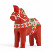 Grannas A. Olsson Hemslojd（グランナス オルソン ヘムスロイド）は、1922年にスウェーデン・ダーラナ地方ヌスナスで創業した世界最古のダラホース工房です。創業者のアンダース オルソン氏は、当初家族経営のパン屋から木工品製造へと転換し、弟らと協力してダラホースの生産を始めました。ひとつずつ選別されたスロースギ材（シルヤン湖周辺の赤松）を使い、木型の挽きから手彫り、下地塗装、さらに熟練のリップル（波模様）ペインターによるフリーハンド装飾を施します。その後、丁寧にニス仕上げされ、赤や白、青など伝統色に彩られた馬たちは、まさに「スウェーデンの象徴」として世界中の家庭や店舗に愛されています。伝統工房としての格式を受け継ぎつつも、パステルやモノトーン、限定柄などを加えることで、現代のインテリアにもマッチするデザイン性も追求しています。