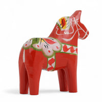 Grannas A. Olsson Hemslojd（グランナス オルソン ヘムスロイド）は、1922年にスウェーデン・ダーラナ地方ヌスナスで創業した世界最古のダラホース工房です。創業者のアンダース オルソン氏は、当初家族経営のパン屋から木工品製造へと転換し、弟らと協力してダラホースの生産を始めました。ひとつずつ選別されたスロースギ材（シルヤン湖周辺の赤松）を使い、木型の挽きから手彫り、下地塗装、さらに熟練のリップル（波模様）ペインターによるフリーハンド装飾を施します。その後、丁寧にニス仕上げされ、赤や白、青など伝統色に彩られた馬たちは、まさに「スウェーデンの象徴」として世界中の家庭や店舗に愛されています。伝統工房としての格式を受け継ぎつつも、パステルやモノトーン、限定柄などを加えることで、現代のインテリアにもマッチするデザイン性も追求しています。