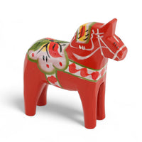 Grannas A. Olsson Hemslojd（グランナス オルソン ヘムスロイド）は、1922年にスウェーデン・ダーラナ地方ヌスナスで創業した世界最古のダラホース工房です。創業者のアンダース オルソン氏は、当初家族経営のパン屋から木工品製造へと転換し、弟らと協力してダラホースの生産を始めました。ひとつずつ選別されたスロースギ材（シルヤン湖周辺の赤松）を使い、木型の挽きから手彫り、下地塗装、さらに熟練のリップル（波模様）ペインターによるフリーハンド装飾を施します。その後、丁寧にニス仕上げされ、赤や白、青など伝統色に彩られた馬たちは、まさに「スウェーデンの象徴」として世界中の家庭や店舗に愛されています。伝統工房としての格式を受け継ぎつつも、パステルやモノトーン、限定柄などを加えることで、現代のインテリアにもマッチするデザイン性も追求しています。