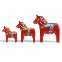 Grannas A. Olsson Hemslojd（グランナス オルソン ヘムスロイド）は、1922年にスウェーデン・ダーラナ地方ヌスナスで創業した世界最古のダラホース工房です。創業者のアンダース オルソン氏は、当初家族経営のパン屋から木工品製造へと転換し、弟らと協力してダラホースの生産を始めました。ひとつずつ選別されたスロースギ材（シルヤン湖周辺の赤松）を使い、木型の挽きから手彫り、下地塗装、さらに熟練のリップル（波模様）ペインターによるフリーハンド装飾を施します。その後、丁寧にニス仕上げされ、赤や白、青など伝統色に彩られた馬たちは、まさに「スウェーデンの象徴」として世界中の家庭や店舗に愛されています。伝統工房としての格式を受け継ぎつつも、パステルやモノトーン、限定柄などを加えることで、現代のインテリアにもマッチするデザイン性も追求しています。