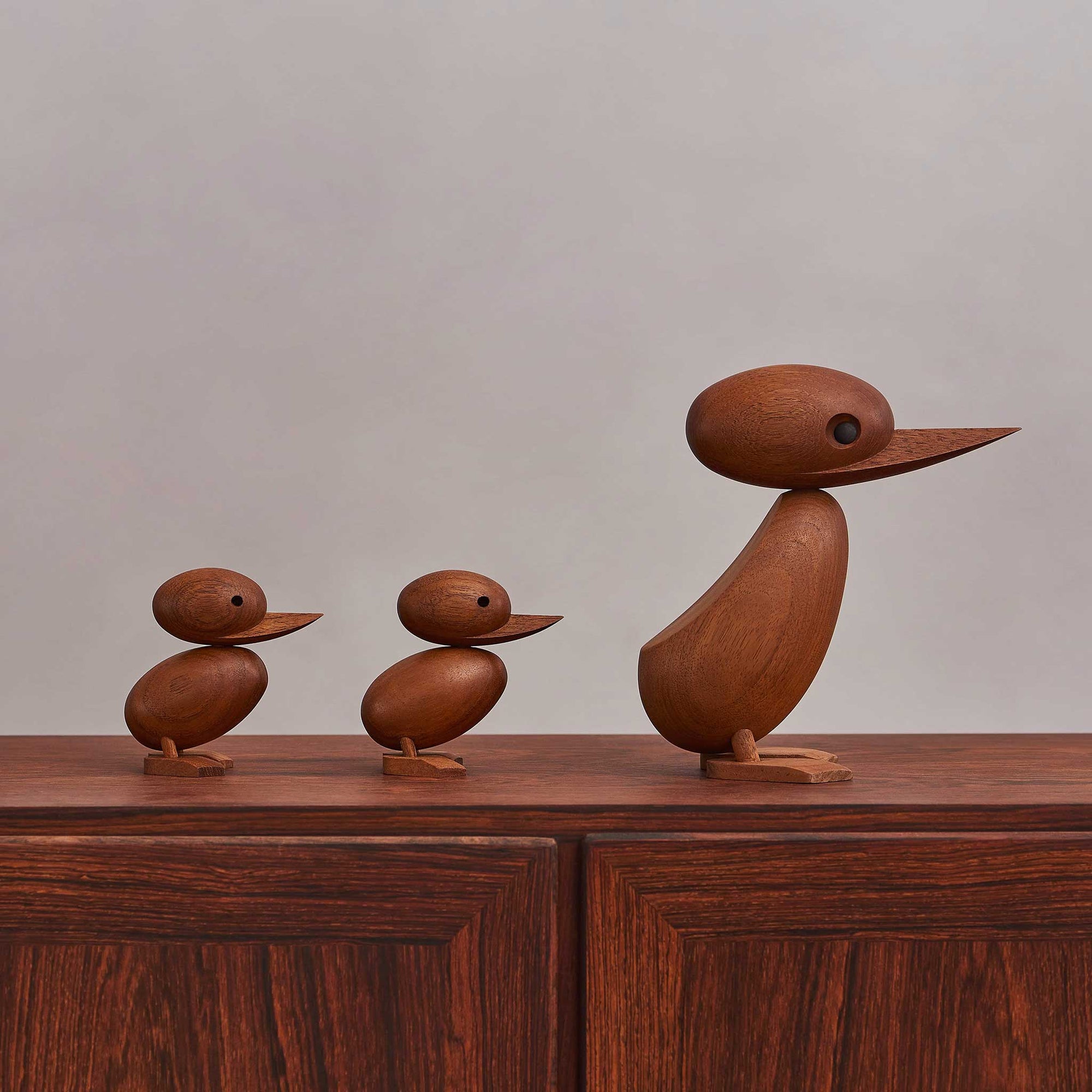 1959年、デンマーク・フレデリクスベアのラッシュアワーのこと。一家のカモがにぎやかな通りに迷い込みました。警官は車と歩行者の交通を止めて、このかわいらしいカモの家族が無事に通れるように道を譲りました。この微笑ましい出来事は、地元新聞の一面を飾り、デンマークの人々の心を魅了しました。この物語に心を打たれたのが、デンマークの建築家ハンス・ブリングです。彼は感動を形にしたいと、この「ダックとダックリング」をデザインしました。窓辺に飾ることができるよう、手作業で作られたチーク無垢材の製品です。頭部は動かすことができ、洗練された美しい仕上がりとなっています。ご自宅で、あなただけのカモの家族を作ってみてください。