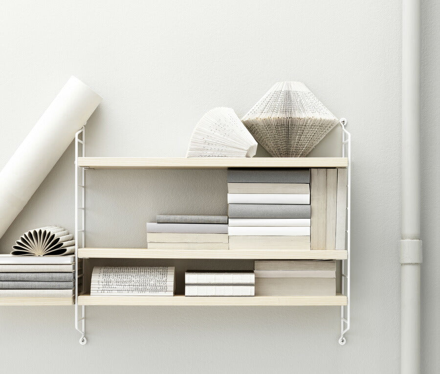 北欧スウェーデンデザインのストリングポケットシェルフ。CDや文庫本などを見た目にも美しく収納できるスリムな棚です。ストリングは拡張性に優れており自分の好み通りフレキシブルに組み合わせることが可能です。また軽量化にも優れており扱いやすい半面十分な安定性を兼ね備えています。北欧の家庭では大変人気のある棚であり、オフィスレイアウトなどにも適しています。空間に配置することにより、部屋に圧迫感を与えないのも特徴です。日本の住宅に取り付ける場合、ネジを取り付ける箇所の壁紙を予め1cm各程度小さく剥がしておき、ネジを取り外した際壁紙を再度貼りなおすことで目立たなくすることができると思います。