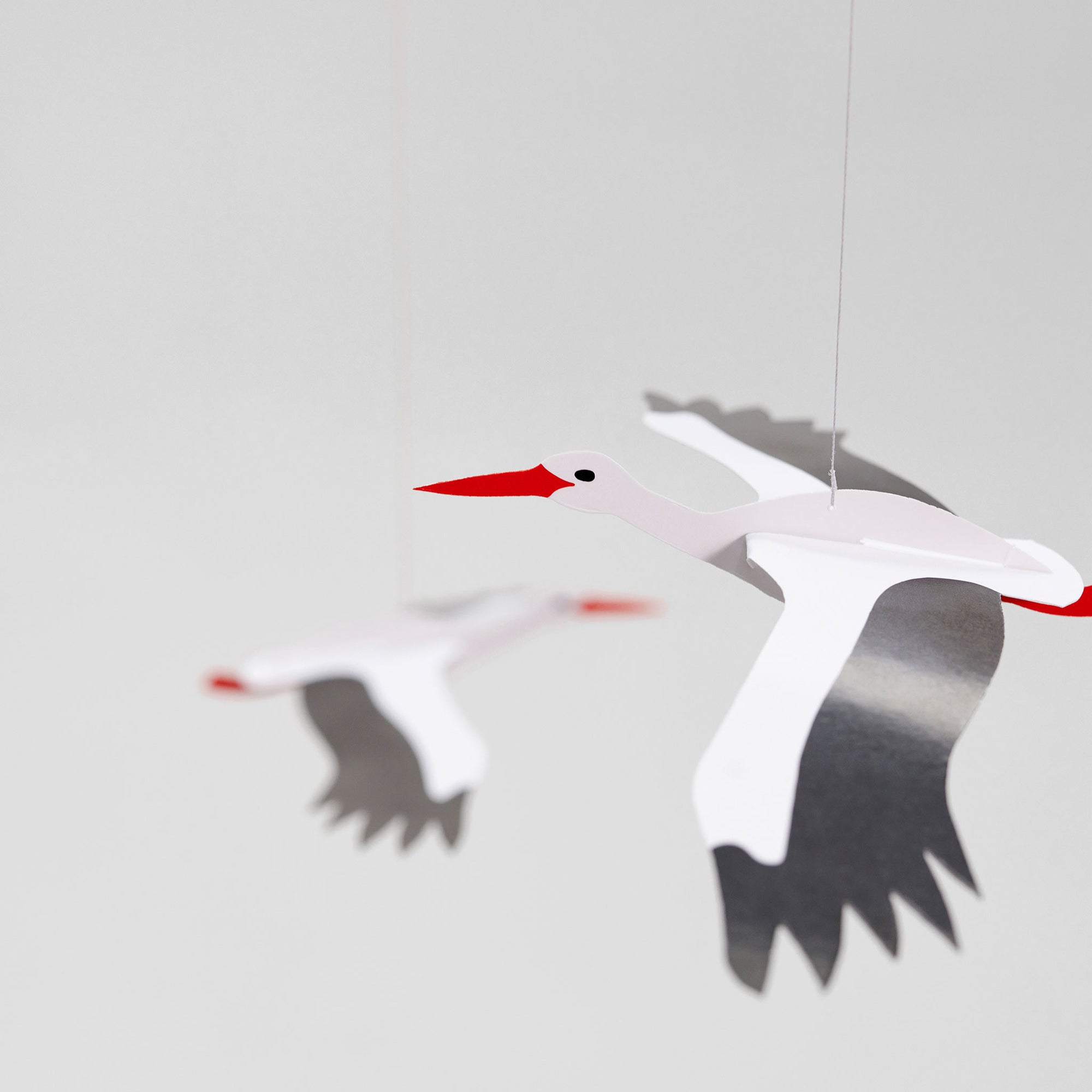Flensted Mobiles（フレンステッド・モビール）は、1953年創業のデンマーク発・モビール専門ブランド。北欧デザインの文脈に立脚し、造形・質量配分・回転慣性を最適化して、わずかな気流でも自律的に表情を変える構成美を追求します。各パーツは重心とトルクの釣り合いを精密に設計し、静止と運動のあいだを往還する“動く彫刻”として空間に時間軸を付与。代表作「Lucky Storks」から幾何学、鳥類、気球まで多彩で、紙・ステンレス・木材の軽量構造は施工負荷が小さく、住宅・商業・ホスピタリティ・キッズ空間に適合します。現在もデンマーク国内で手作業組立・品質管理を徹底し、視覚ノイズを抑えた運動リズムが集中・鎮静・遊び心をもたらします。北欧インテリアの天井飾りや吊り下げモビールとして、リビング・子供部屋・出産祝いギフトに最適なデンマーク製の正規品です。